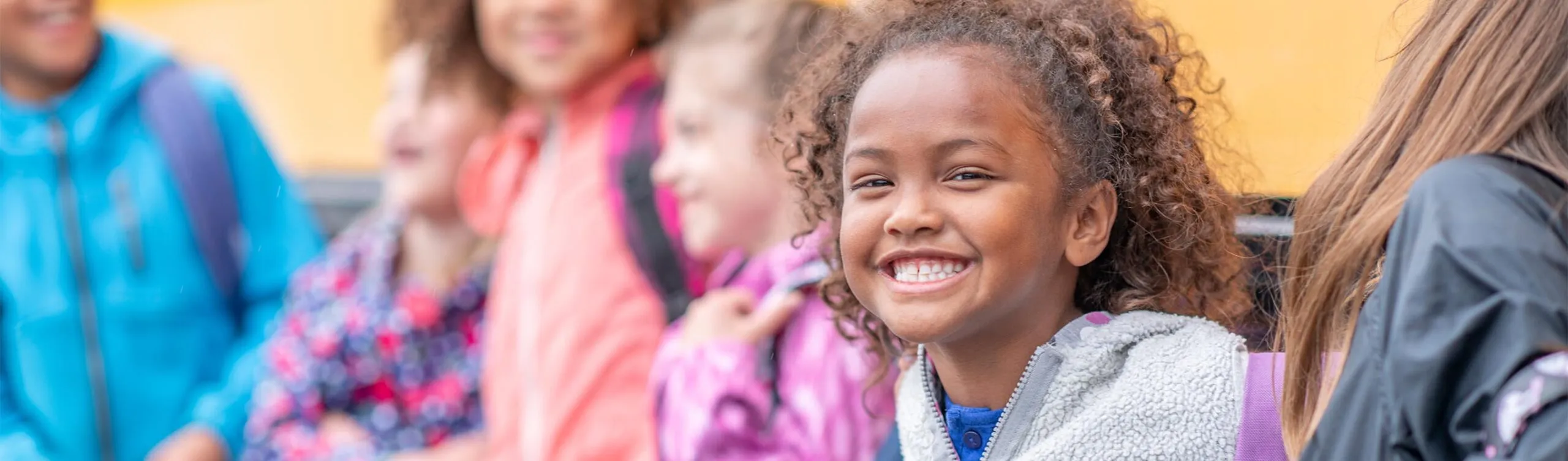 Girl smiling by school bus