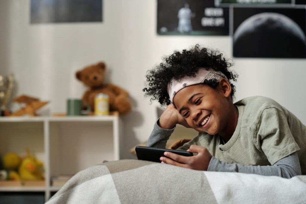 child on bed smiling at phone screen