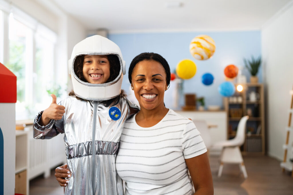 Portrait of a teacher and her a child in a space suit during playtime