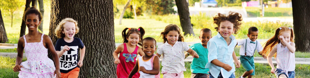 a group of preschoolers running on the grass in the summer